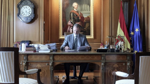 El rey en su despacho junto a su antecesor Carlos II al fondo.