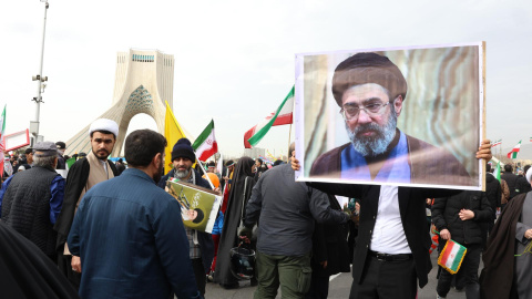 Un iraní sujeta un retrato de Mojtaba Jameneí, elegido sucesor de su padre como líder supremo de Irán, en una marcha a su favor por las calles de Teherán.
