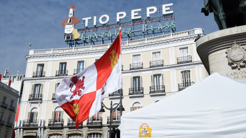 Una bandera de Castilla y León, frente al anuncio de Tío Pepe, durante un acto reivindicativo de Jóvenes de Castilla y Léon contra la despoblación, en la Puerta del Sol, a 5 de febrero de 2022.