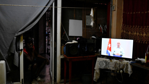 Un hombre observa al presidente cubano Miguel Díaz-Canel mientras afirma que han iniciado conversaciones con EEUU.