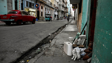 Un hombre y su gato se sientan en la puerta de su casa en La Habana este 13 de marzo de 2026.
