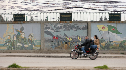 Una motocicleta pasa junto a unos murales de combatientes kurdos en Qamishli (Siria). Una motocicleta pasa junto a unos murales de combatientes kurdos en Qamishli (Siria).