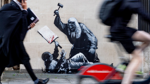 Obra de Banksy en Londres en 2025 muestra a un juez apaleando con un mazo a un manifestante que sujeta una pancarta.