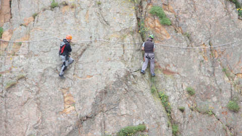 Dos escaladors fent el tram més difícil de la via ferrada de Sant Feliu de Guíxols.