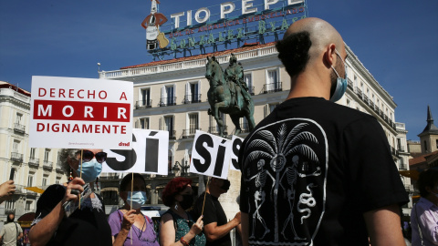 Un grupo de personas se reúne sosteniendo pancartas y carteles durante la concentración de la asociación Derecho a Morir Dignamente (DMD)