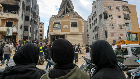 Periodistas y ciudadanos congregados alrededor de un edificio alcanzado por los ataques aéreos israelíes en los suburbios del sur de Beirut, Líbano.