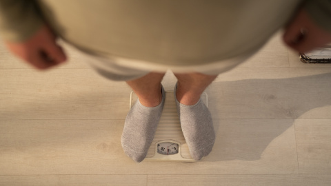 Un hombre consulta su peso en una báscula Un hombre consulta su peso en una báscula