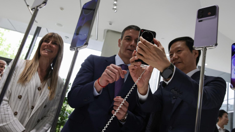 El presidente del Gobierno, Pedro Sánchez, y su mujer, Begoña Gómez, observan teléfonos inteligentes junto al CEO de Xiaomi, Lei Jun, en  Pekín (China).