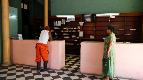 Dos personas esperan a ser atendidos en una farmacia de La Habana.