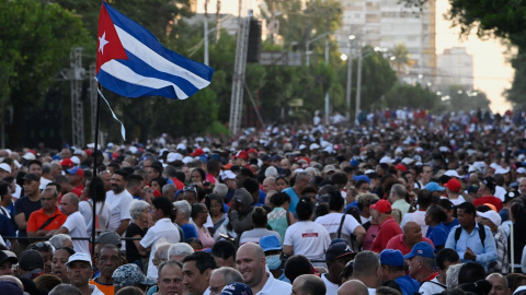 Una bandera cubana ondea sobre una multitud por la ceremonia que conmemora el 65 aniversario de la Revolución.