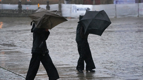 Personas intentan sujetar sus paraguas en Santiago de Compostela.