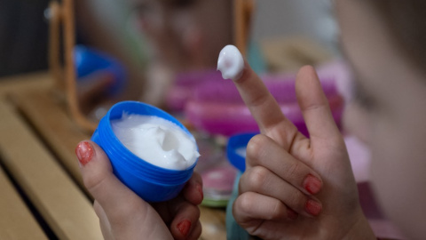Una niña con una crema para la cara.