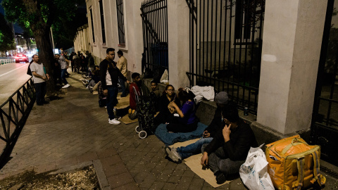 Varias personas hacen cola nocturna para conseguir el certificado de vulnerabilidad en una Oficina de Asistencia en Materia de Registro, a 21 de abril de 2026, en Madrid.
