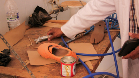 Foto_2-2 Salik Abidi Bashir, director del Centro Nacional de Ortopedia y Fisioterapia de Rabuni muestra el material que está utilizando para fabricar el zapato ortopédico que necesita uno de sus pacientes. El bote de pegamento que hay sobre la mesa está vacío. (30.04.26)