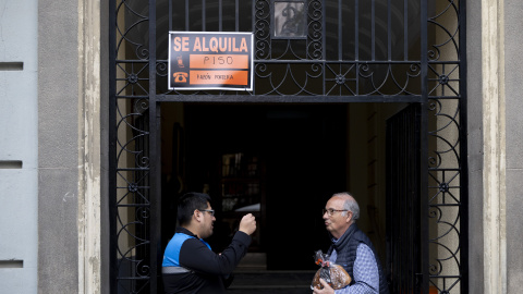 Imagen de archivo de dos hombres charlando bajo un cartel de 'se alquila' en un portal de Madrid.