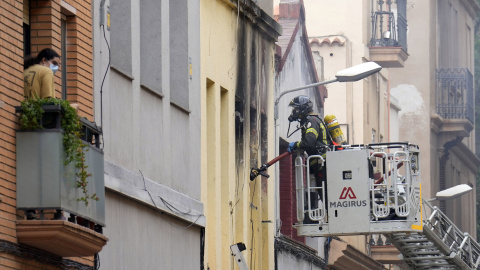 Un bombero procede al desalojo de un vecino del edificio donde ha explotado una bombona de butano en la calle Venero de Barcelona.