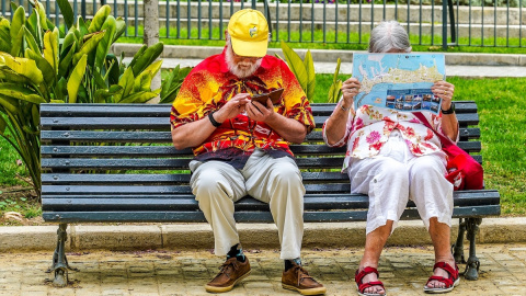 Una pareja de turistas consultan un mapa en un banco de Cádiz.