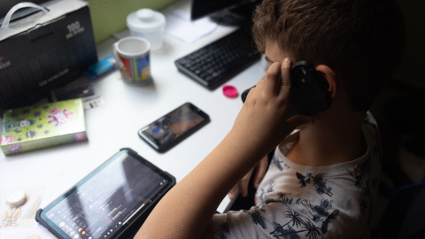 Foto de archivo de un niño usando el teléfono móvil y una tablet. Foto de archivo de un niño usando el teléfono móvil y una tablet.
