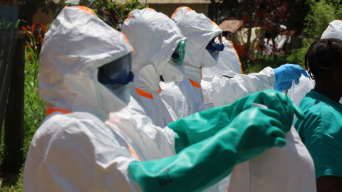 Trabajadores médicos visten trajes de protección antes de desinfectar una zona en Mongbwalu.