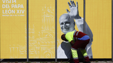 Un operario coloca una valla con motivo de la visita del Papa León XIV a España.