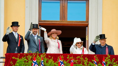 La familia real noruega saluda desde un balcón.