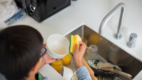 Imagen de un niño ayudando a fregar los platos. Imagen de un niño ayudando a fregar los platos.