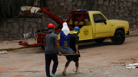 Dos personas llevan una figura religiosa por las calles de Caracas.