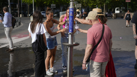 Personas en París hidratándose este martes en París durante la ola de calor.