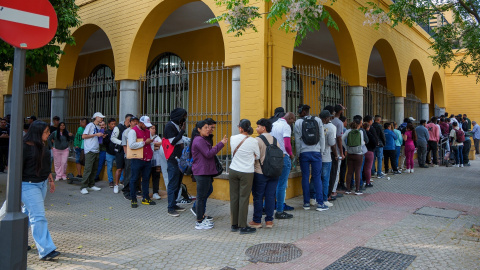 Personas migrantes hacen cola para la tramitación de su regularización administrativa en Sevilla
