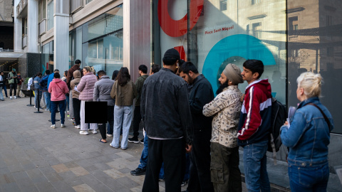Varias personas migrantes hacen cola en una oficina para presentar los documentos para su regularización. Varias personas migrantes hacen cola en una oficina para presentar los documentos para su regularización.