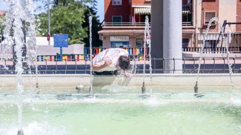 Una persona se refresca en una fuente en Madrid.
