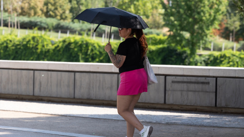 Una persona se refugia del sol con un paraguas frente a la ola de calor en Madrid. Una persona se refugia del sol con un paraguas frente a la ola de calor en Madrid.