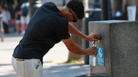 ola-de-calor Una persona se refresca en una fuente.
