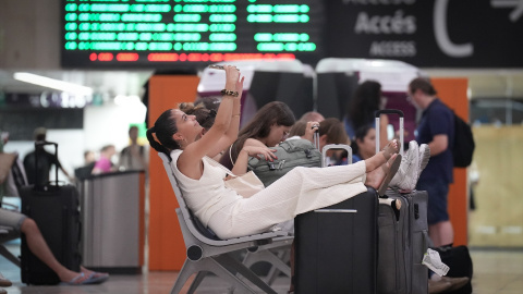 Varias personas con maletas, en la estación de Sants.