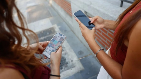 Dos jóvenes miran sus teléfonos móviles en Madrid. Dos jóvenes miran sus teléfonos móviles en Madrid.