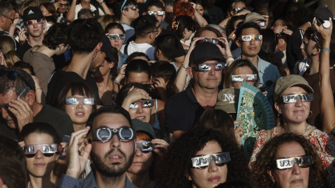 Una multitud de personas espera con gafas protectoras el comienzo del eclipse de Sol en Madrid.