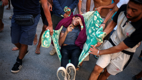 Migrantes transportan a otro migrante, quien según afirman resultó herido cuando la policía y el ejército españoles intentaron contenerlos en una zona de la playa. Migrantes transportan a otro migrante, quien según afirman resultó herido cuando la policía y el ejército españoles intentaron contenerlos en una zona de la playa.