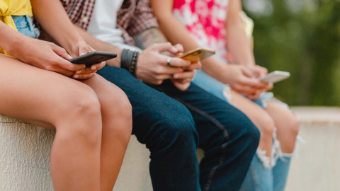 Un grupo de niños y adolescentes utilizan sus móviles sentados en la calle. Un grupo de niños y adolescentes utilizan sus móviles sentados en la calle.