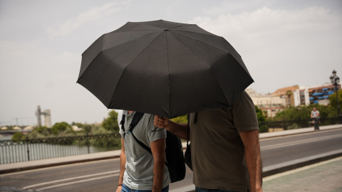 Personas paseando con sombrillas, a 23 de junio de 2026, en Sevilla.