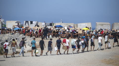 Decenas de migrantes caminan por la playa del Trampolín, a 31 de agosto de 2026.