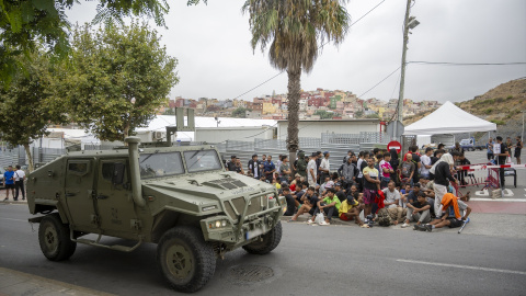 Un blindado militar pasa junto a una cola de personas migrantes, a 1 de septiembre de 2026, en Ceuta. Un blindado militar pasa junto a una cola de personas migrantes, a 1 de septiembre de 2026, en Ceuta.