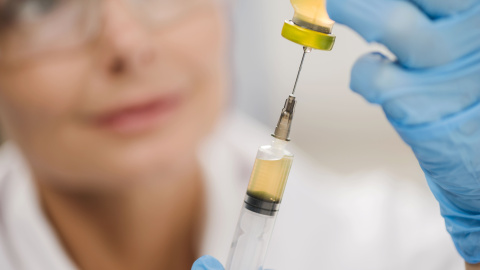 high-angle-defocused-female-scientist-using-syringe (1) Una sanitaria con una jeringuilla. Imagen de archivo.