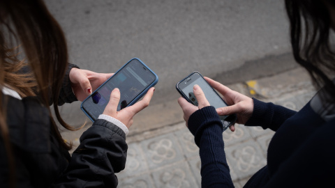 Dos niñas usan el teléfono móvil. Dos niñas usan el teléfono móvil.