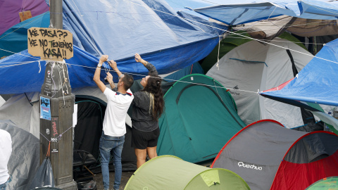 Dos personas protegen las tiendas de campaña con lonas en Sol, a 1 de octubre de 2026. Dos personas protegen las tiendas de campaña con lonas en Sol, a 1 de octubre de 2026.