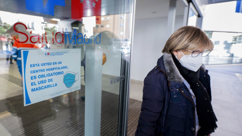 Una mujer con mascarilla sale del hospital.