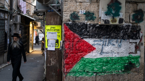 Un hombre judío ultraortodoxo pasa junto a una bandera palestina pintada en una pared del barrio de Jerusalén, una semana antes de que se celebren las elecciones al Knéset del 27 de octubre de 2026. Un hombre judío ultraortodoxo pasa junto a una bandera palestina pintada en una pared del barrio de Jerusalén, una semana antes de las elecciones al Knéset del 27 de octubre de 2026.