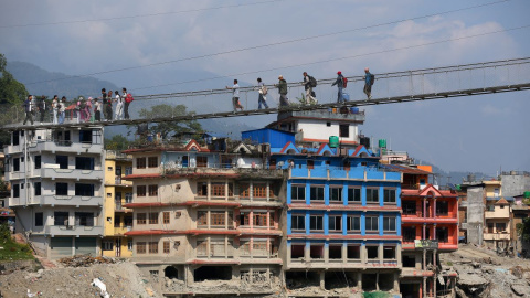 Imagen de archivo de varias personas cruzando un puente colgante instalado tras las inundaciones en la región fronteriza entre el Tíbet y Nepal.
