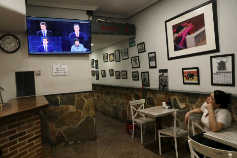 Una mujer observa el debate electoral a cuatro en TVE, en un televisión en un bar en Madrid. REUTERS/Susana Vera
