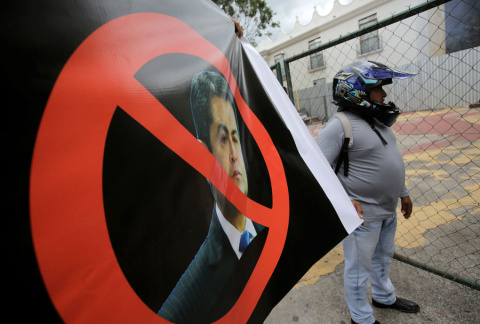 Un manifestante con un cartel exigiendo la salida del presidente, Juan Orlando Hernández, señalado por la Fiscalía de Nueva York en una presunta conspiración para usar dinero del narcotráfico con el fin de mantenerse en el poder. REUTERS/Jorge Cabrer