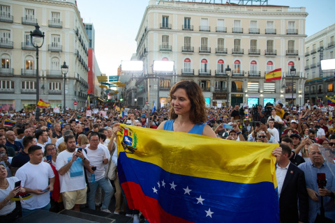 La presidenta de la Comunidad de Madrid, Isabel Díaz Ayuso, sostiene una bandera de Venezuela durante una protesta contra el Gobierno de Nicolás Maduro, en la madrileña Puerta del Sol, el pasado  agosto de 2024. EUROPA PRESS/Jesús Hellín
